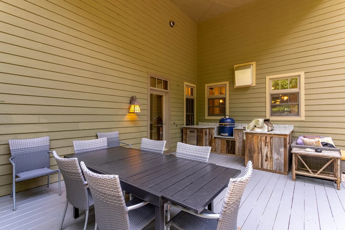 An inviting outdoor living area featuring a large dining table, an outdoor kitchen with grilling stations, and comfortable seating. The setup is perfect for social gatherings, family meals, or al fresco feasts under the stars.