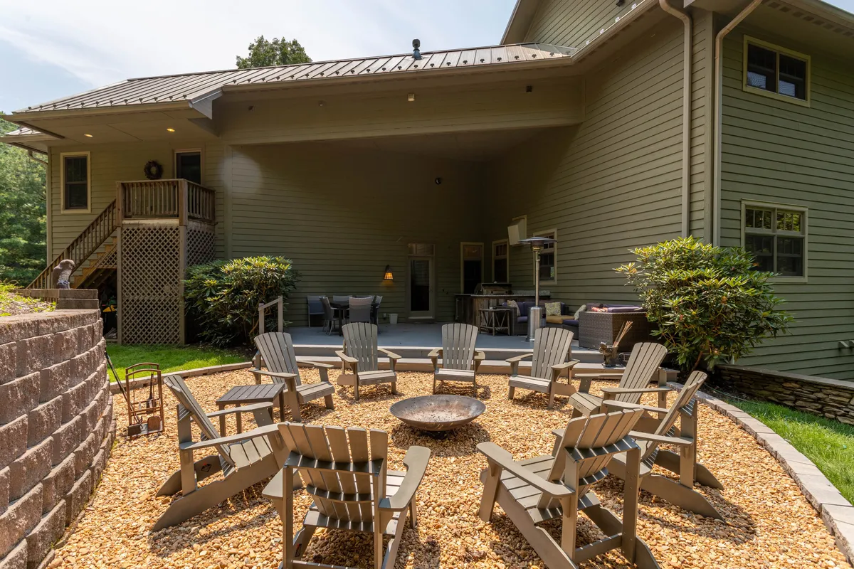 This image displays a cozy outdoor fire pit area with Adirondack chairs arranged for social gatherings on the back porch, ideal for stargazing, sharing stories, or warming up after an adventurous day in the mountains.
