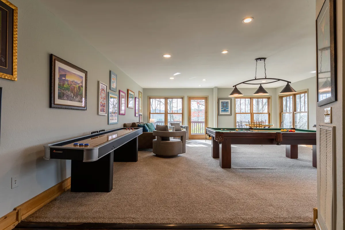 A vibrant game room interior with a pool table, air hockey table, comfortable seating area, and colorful artwork adorning the walls. The space is bright and designed for fun, family bonding, and relaxation.